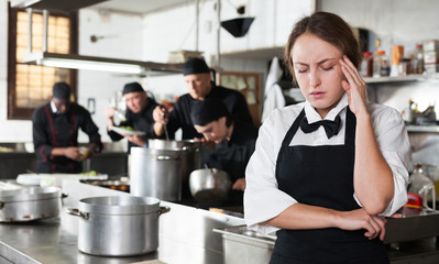 Tired and upset waitress in kitchen of restaurant