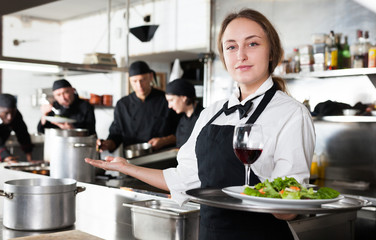 Fototapeta na wymiar Professional waitress holding serving tray at restaurant kitchen