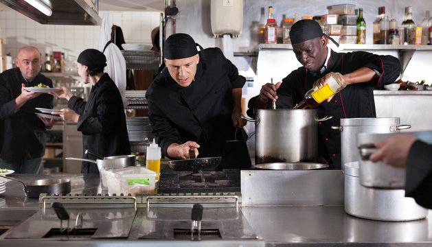 Chef with team preparing food in kitchen of restaurant