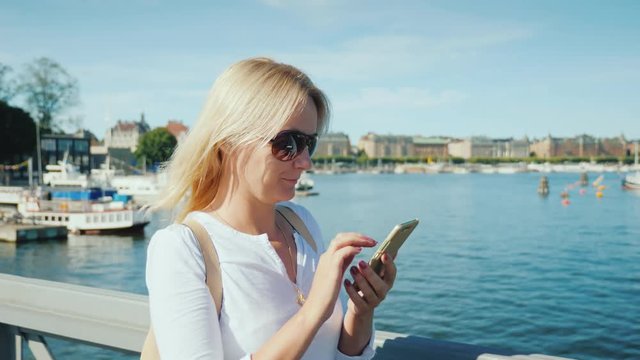 Woman with a smartphone walking along the embankment of Stockholm