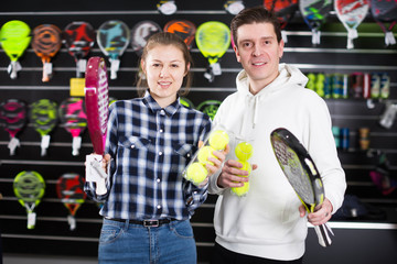 Smiling couple choosing padel racket and balls