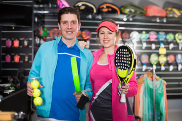 Girl and man choosing padel racket and balls