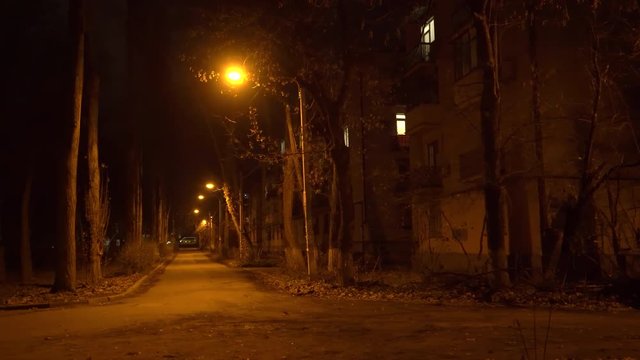 Empty city street with street lights at night in late autumn. Old buildings and dark park.