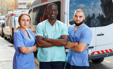 Fototapeta na wymiar Portrait of ambulance team of three standing near ambulance car
