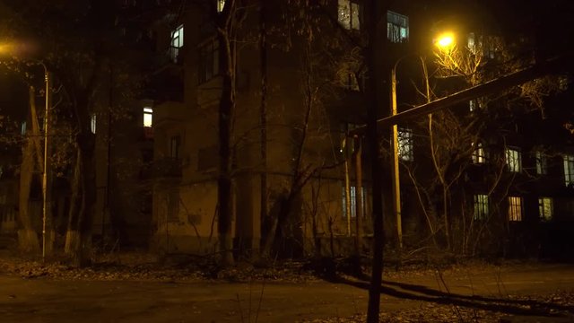 Empty city street with street lights at night in late autumn. Old buildings and dark park.