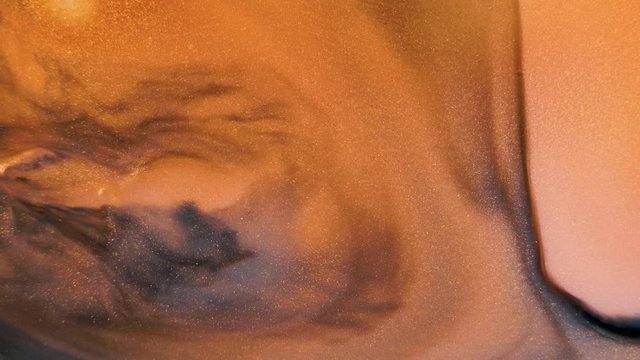 Colorful golden sand organically moves in colorful liquid