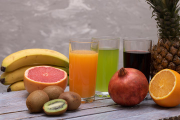 three glasses juices and raw fruits