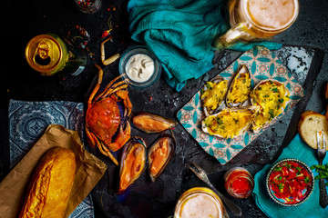 baked oysters with cheese and other seafood with glasses of beer on the table