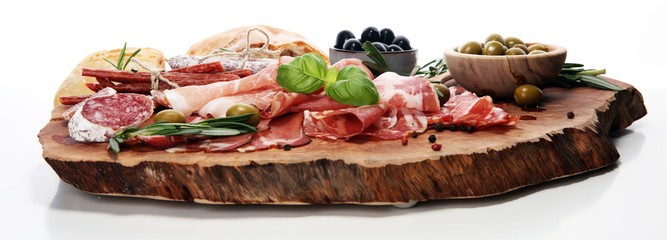 Marble cutting board with prosciutto, bacon, salami and sausages on wooden background. Meat platter