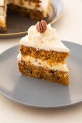 Slice of carrot cake with cream cheese frosting on white table. Copy space. Vegan cake.