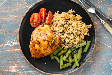 Grilled chicken thighs with bulgur, asparagus beans and tomatoes. Delicious lunch. Copy space.