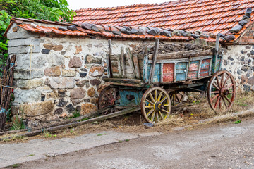Fototapeta na wymiar Loaded with compost colored old cart next to a building wall at the Rhodope Mountains village of Bukovo, Bulgaria on a rainy July day