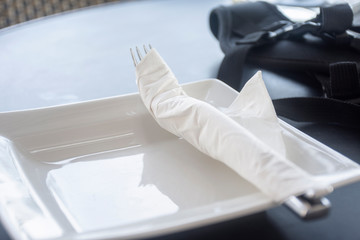 fork in napkin on white dish, restaurant concept