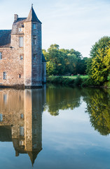 Fototapeta premium The turrets of the 14th century Chateau de Trecesson in the Forest of Paimpont viewed across the large pool by which it is surrounded