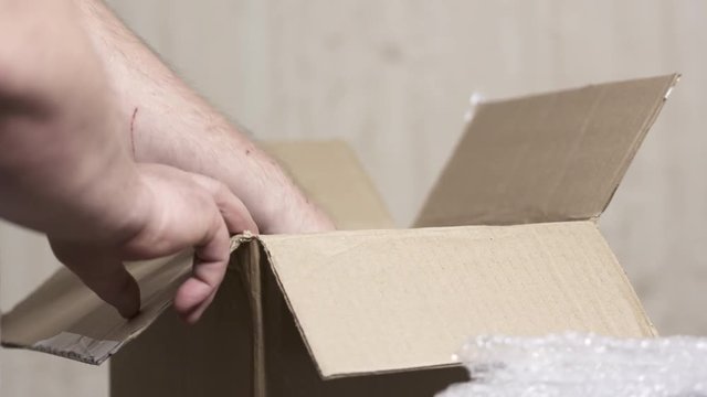 Unpacking unboxing delivered cardboard parcel with some device