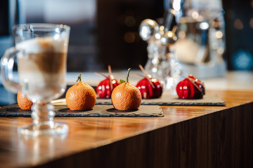 Handmade cakes covered with red glaze and cakes in the form of tangerines