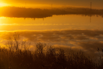 beautiful autumn morning in the countryside near the lake, fog in the distance, beautiful blue sky and cloud reflection in the water
