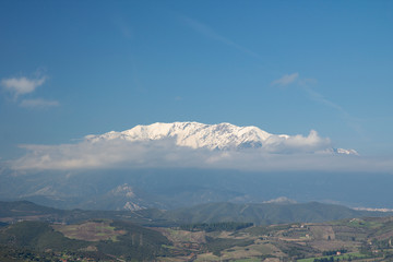 snowed mountain top appearing through the clouds