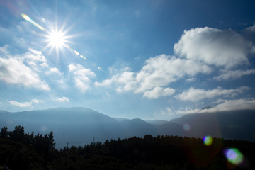 Sun shining with camera lens flare over the mountain top landscape