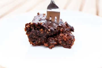 Close up of a vegan chocolate brownie with nuts with a fork