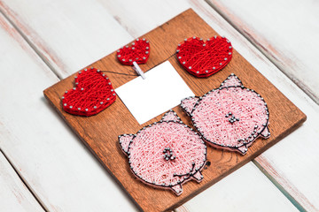 wooden Board with pink pigs and red hearts and text frame on white wooden diagonal background
