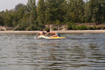 Teenager boys surfing on tropical beach in Europe. Kids on surf board on river wave. Active water sports for kids. Kid swimming with body board photo.