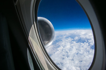 View from the window of the plane onto the wing and engines of a fokker 100 model with a blue sky and white clouds. Sunny weather