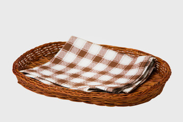 
Brown wicker basket with a brown checkered napkin isolated on a white background