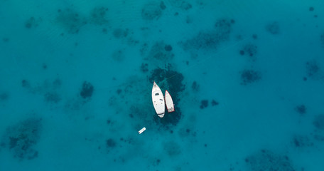 Aerial top view of two isolated boats or yachts moored in the middle of the ocean, sea or a a lagoon. Yacht week, crystal clear water. Concept: luxury yachts on turquoise water, travel agency