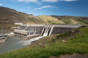 The Clyde hydroelectric power dam spilling large amounts of excess water from two of its four spillways. Clyde, Otago, New Zealand.