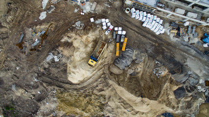 Obraz premium Aerial view of construction site with a huge truck and a lot of sand. Heavy machinery, heavy construction equipment to dig and drill. Sandbox for big boys. Heavy duty.