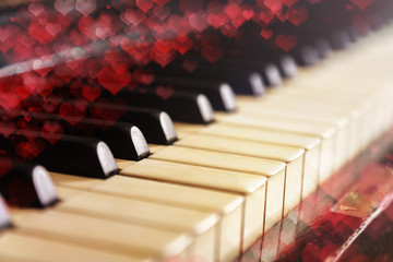 Close-up of old piano keyboard, selective focus, soft toning. Valentine's day background, vintage piano and bokeh hearts
