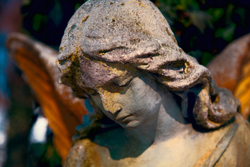 Beautiful angel stone statue with a sweet expression that looks down. Religion, faith, Christianity concept.
