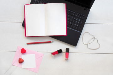 Notebook, laptop and pink envelope on white desk.Valentine day concept.