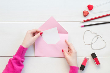 Woman hands holding pink envelope and card.Valentine day concept.