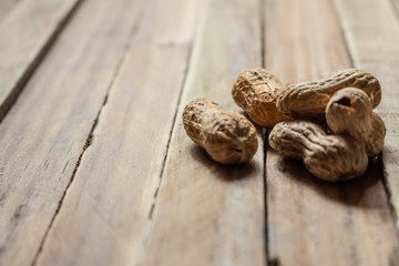 Unpeeled peanuts on a rustic wooden surface. Neutral colors.