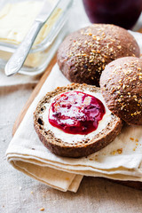 Homemade rye buns with linseeds, sesame and white poppy seeds served with butter and Jostaberry jam