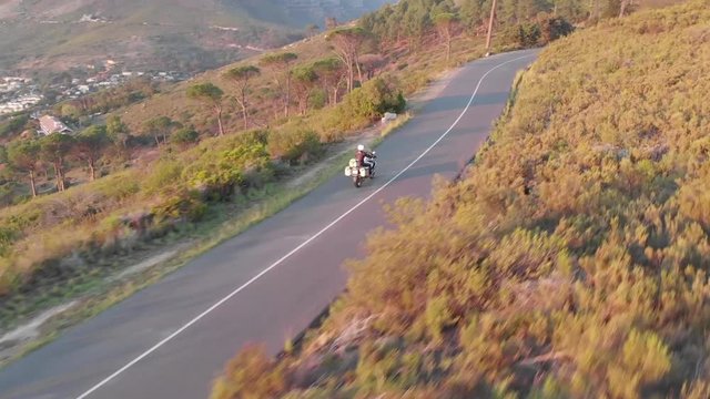 aerial view of a single tour motorcyclist during sunrise on signal hill, Cape Town, with table mountain and lions head