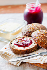 Homemade rye buns with linseeds, sesame and white poppy seeds served with butter and Jostaberry