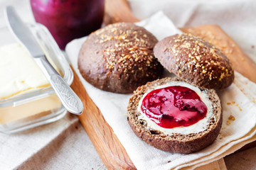 Homemade rye buns with linseeds, sesame and white poppy seeds served with butter and Jostaberry jam