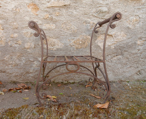 una sedia in ferro battuto davanti a un muro di pietra  - 242198560