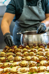 Female Chef Putting Ingredients of Burgers on a Sliced Bread Spread on a Table in Black Gloves