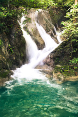 Naklejka premium Erawan waterfall, National Park, Kanchanaburi, Thailand. Close up on water streaming from rocks into a pond.