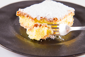 Napoleonka cake - a Polish type of cream pie - sprinkled with powdered sugar, eaten with a fork