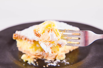 Napoleonka cake - a Polish type of cream pie - sprinkled with powdered sugar, eaten with a fork