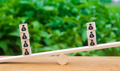 Cubes with pictures of a bag of money. concept of the trade balance, the ratio between profit and expenditure. Economic relations, surplus or deficit in the budget. Trading deal, cost income ratio.