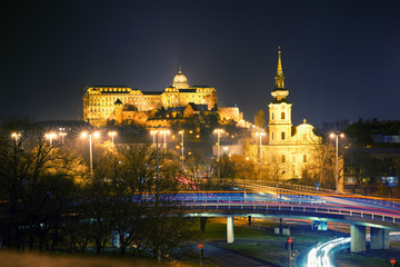 Night view of Saint Catherine of Alexandria Church and Royal Palace of Buda. Road junction and blurred transport lights. Budapest, Hungary