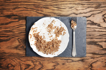 Plate with buckwheat and fork on the blue board and wooden background