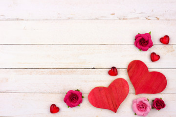 Valentines Day corner border of hearts, flowers and decor against a rustic white wood background. Copy space.