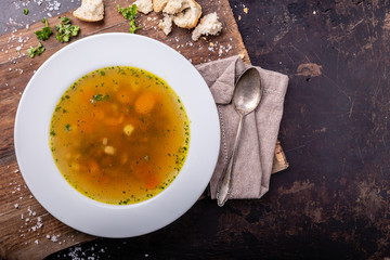 Beef soup with carrots and herbs on a dark background